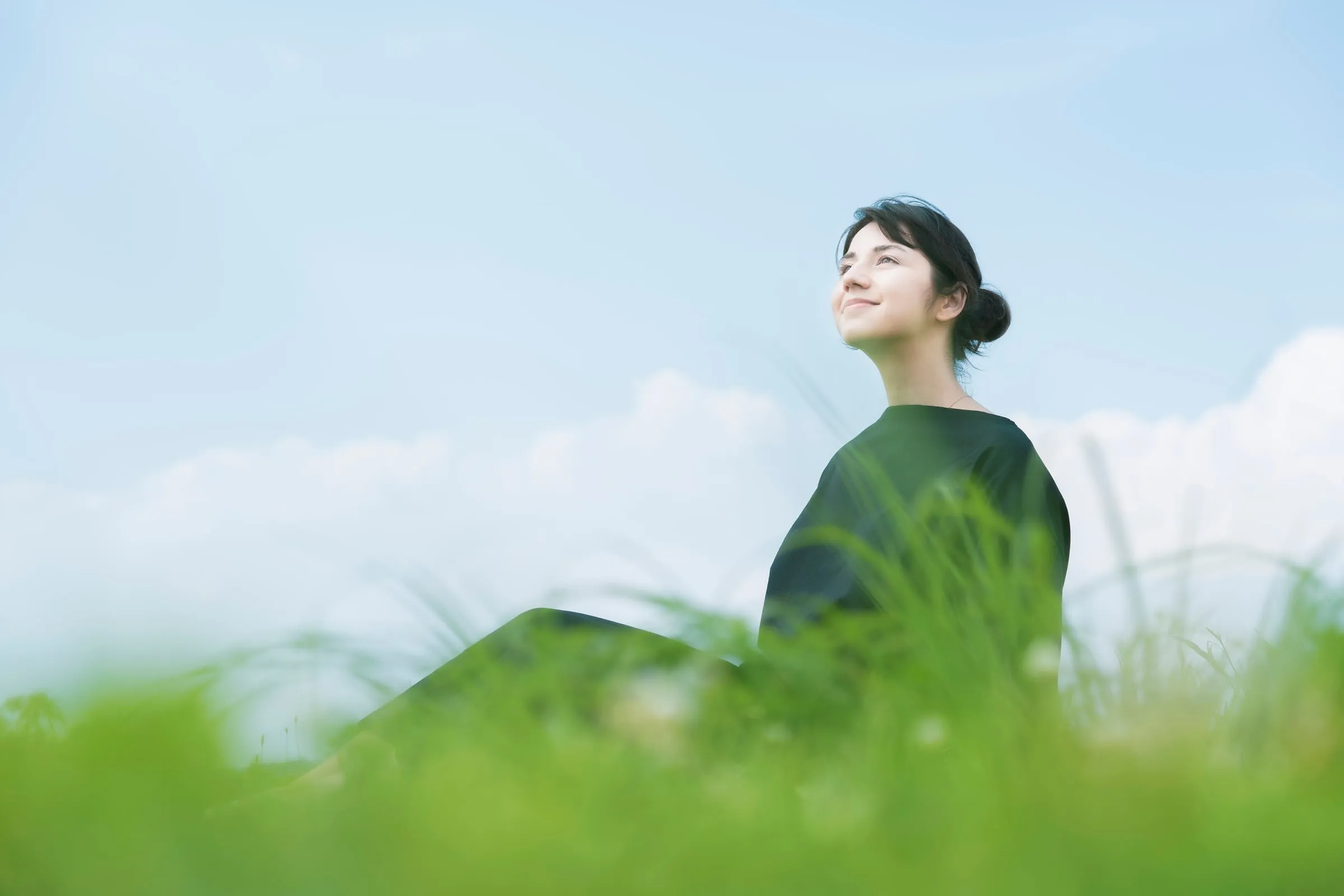 Mujer en un prado mirando al cielo, con los ojos cerrados